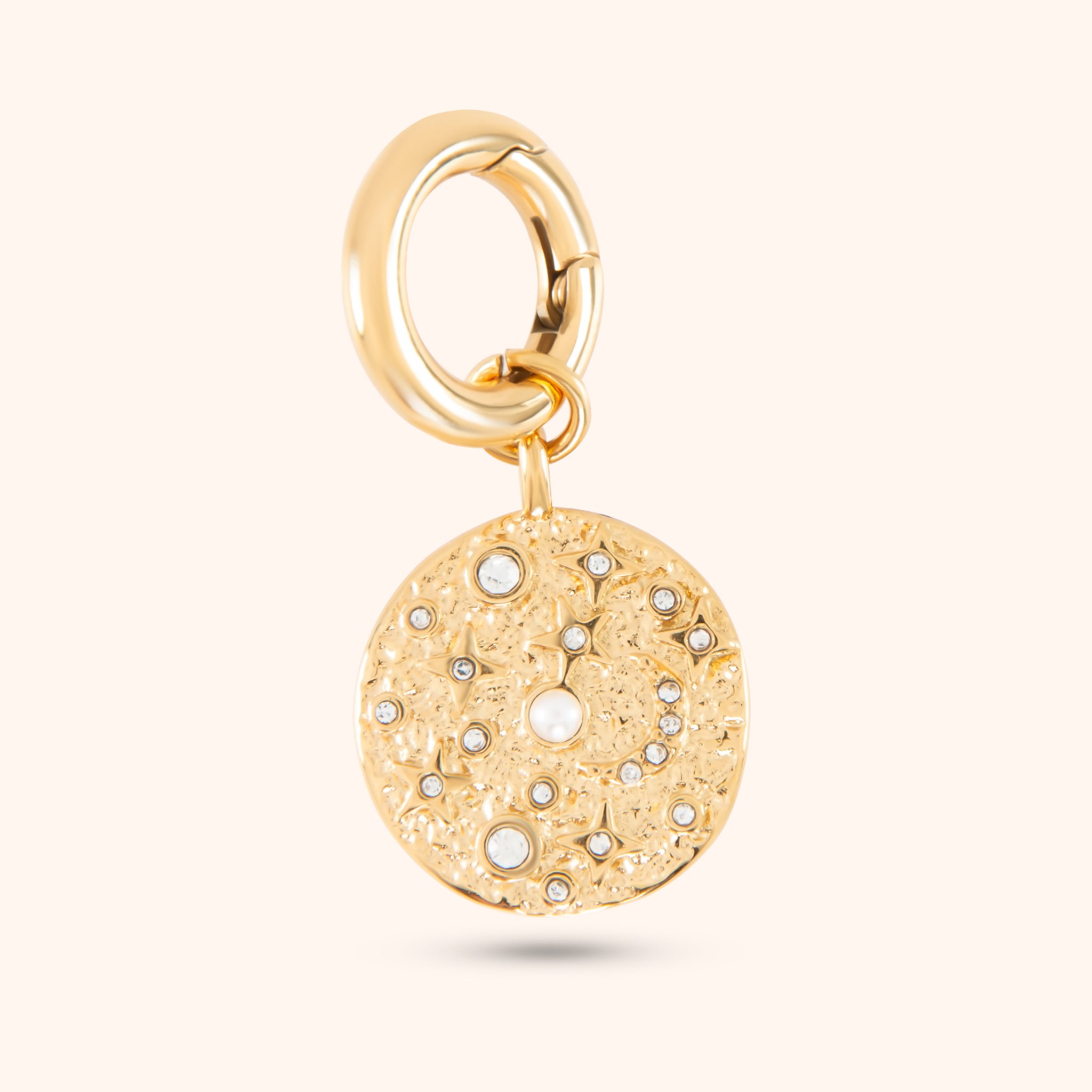 Close-up of the Luna Charm, a gold charm featuring a circular design with moon and star motifs, accented with pearls and cubic zirconia stones, and attached to a small hoop.